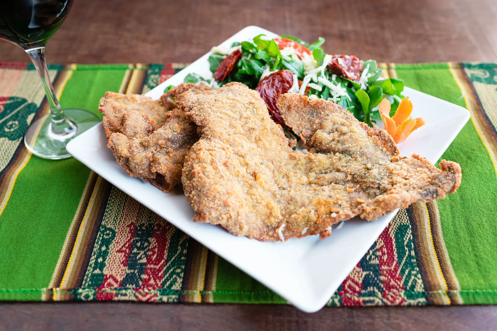 Milanesa de llama con rúcula, queso criollo y tomates secos