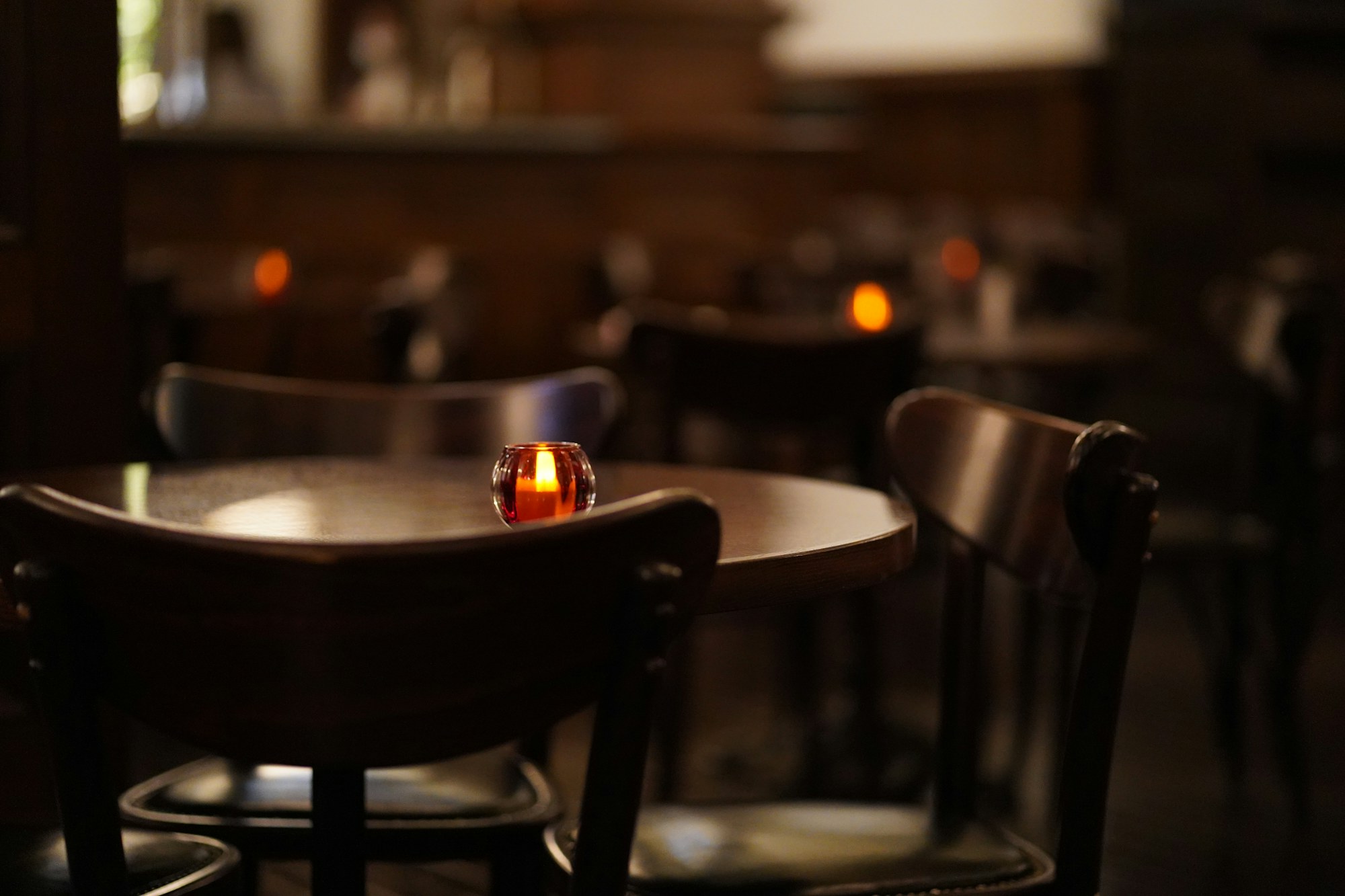 Salón de Don Francesco de noche, con mesas de madera y luz de vela